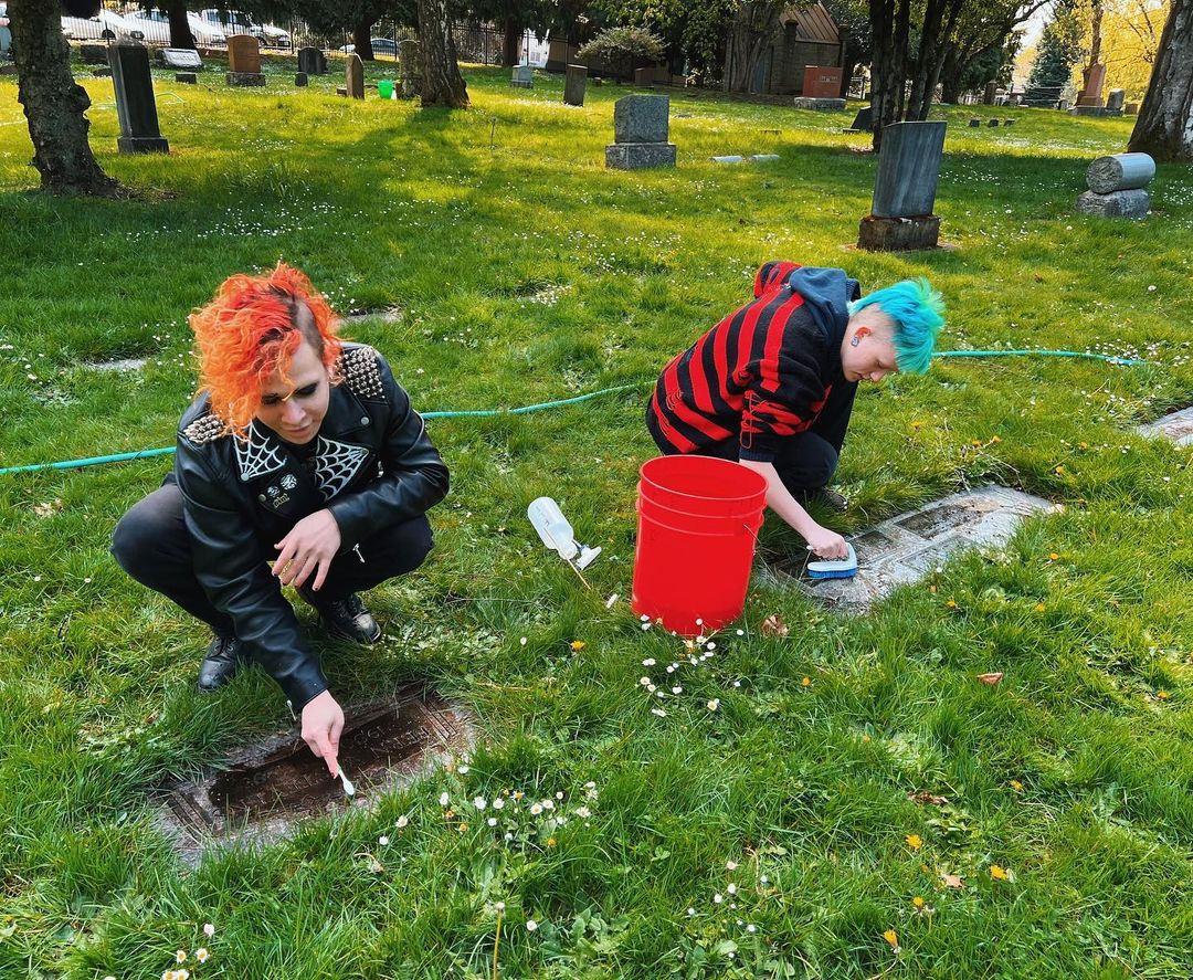 two people cleaning tombstones