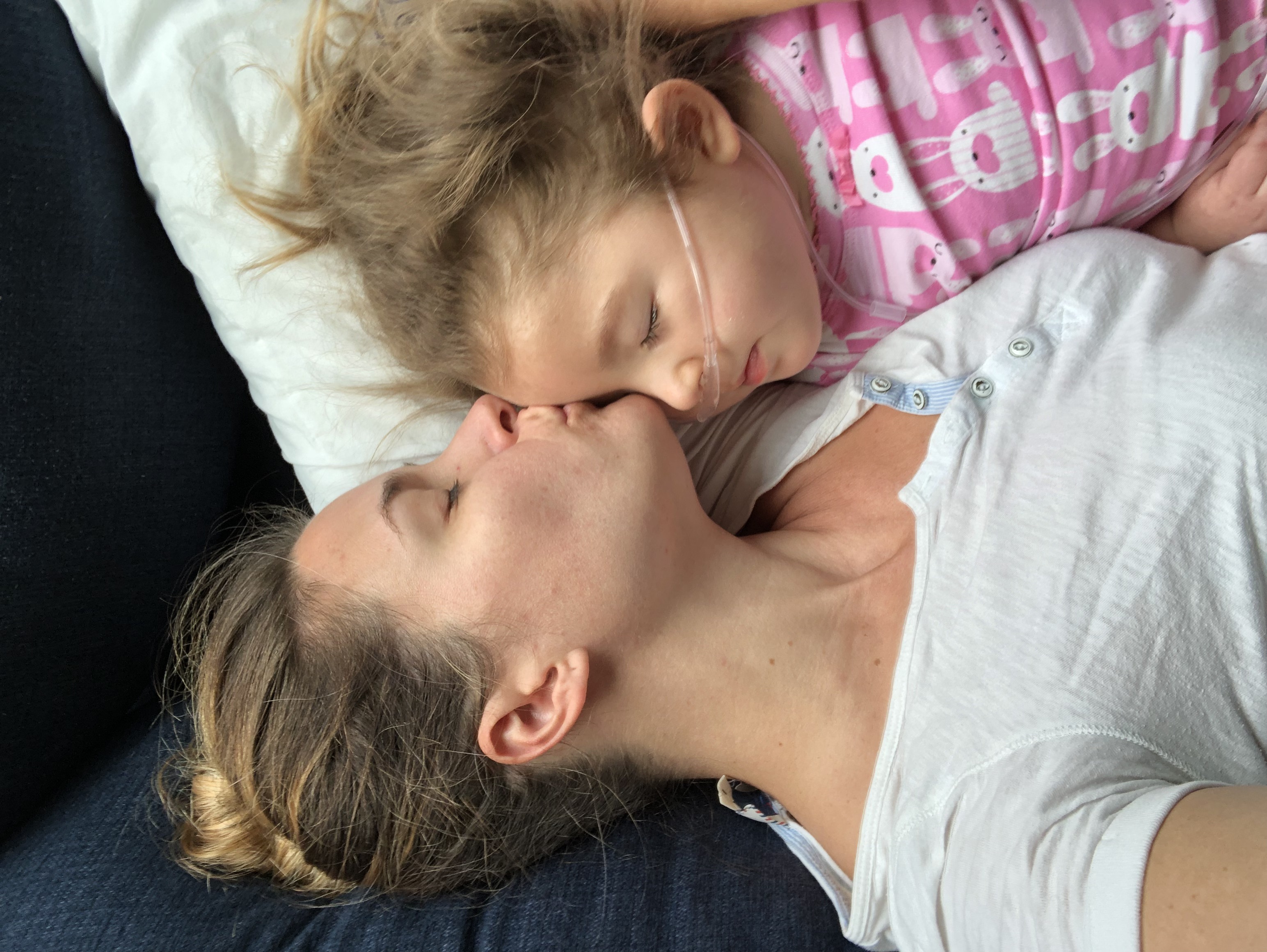 mother kissing her child - the child is on oxygen